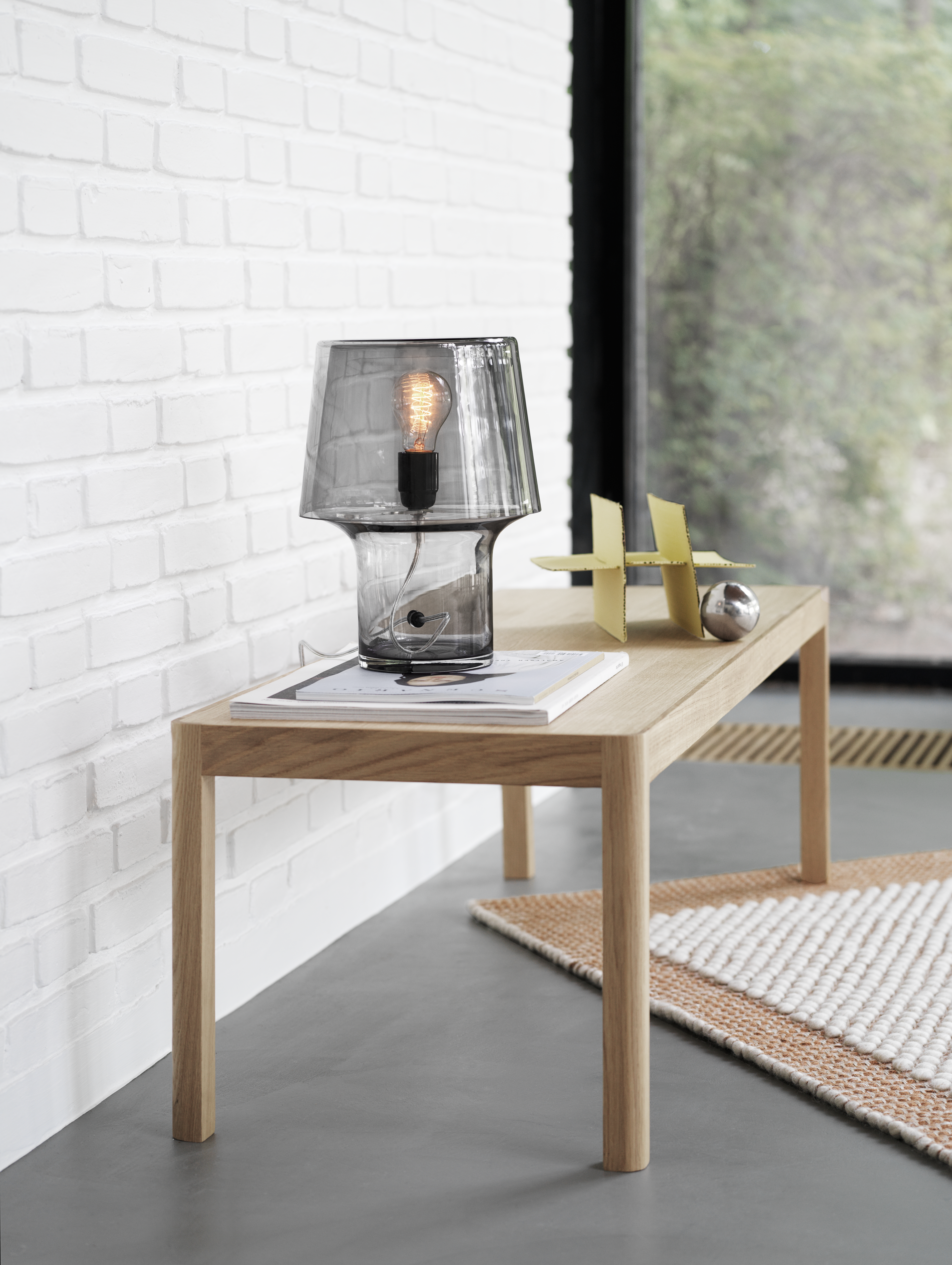 Interior setting featuring the Cosy in Grey Table Lamp, Workshop Table, and Pebble Rug in a warm, minimal composition that highlights soft lighting and natural textures.