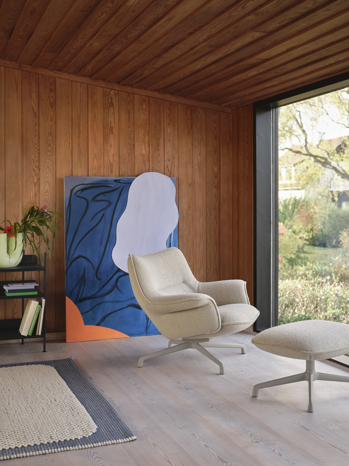 Cozy Doze Lounge Chair in Hearth fabric with a matching pouf, pale blue pebble rug, and green Kink Vase. A stylish relaxation corner for modern homes.