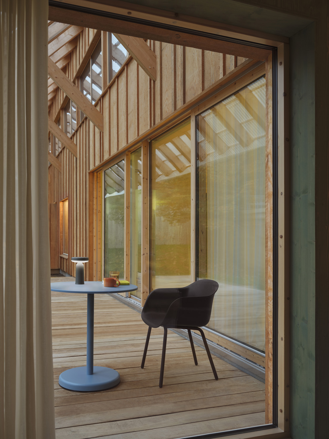 Outdoor-friendly Muuto Fiber Armchair in brown-red paired with a pale blue Linear Steel Café Table. Perfect for patios or garden settings.