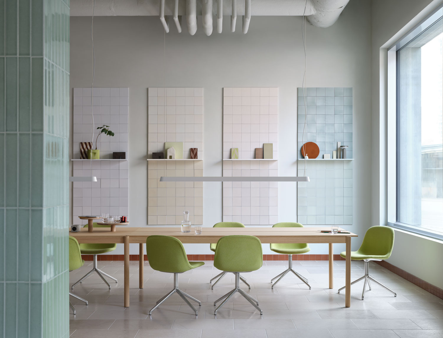 A Muuto workspace featuring a Fiber side chair swivel base with acca 961 upholstery, paired with a Linear System table configuration 2, 110 cm in oak and Linear System Tray in oak. The setup includes a Linear pendant in grey. The clean lines and modern design elements create a sophisticated and functional office environment.