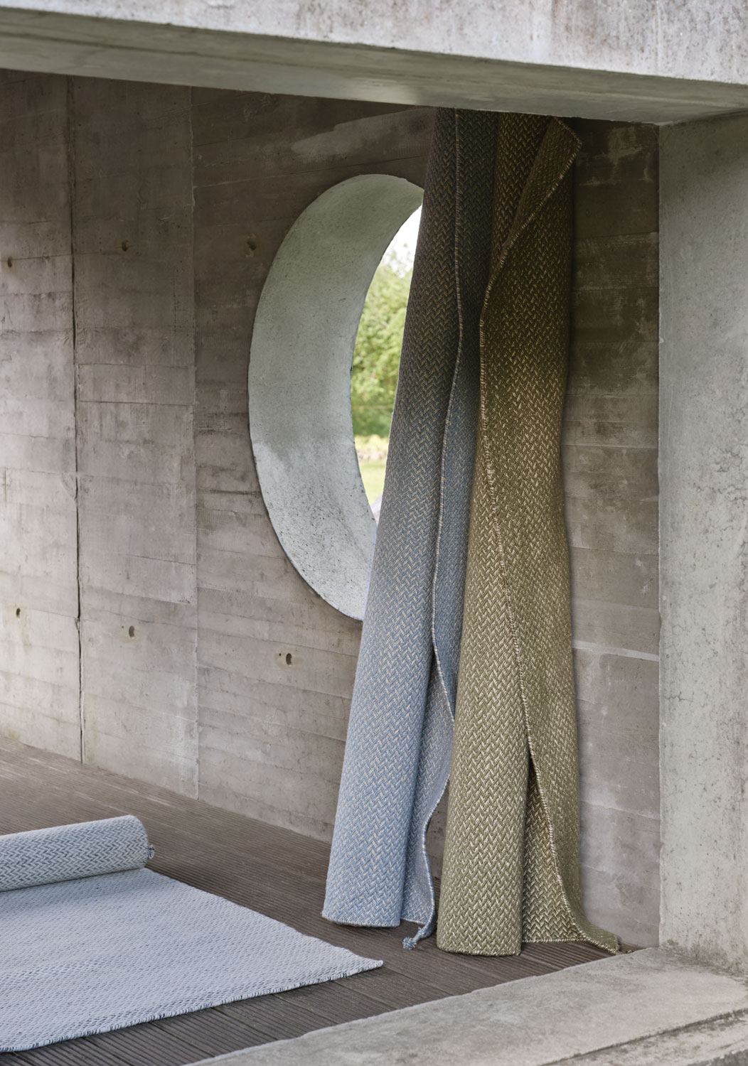A Muuto Ply rug light blue, moss green, made from recycled polyester. The rug’s modern design and soft, muted colors create a stylish and comfortable touch for any space.