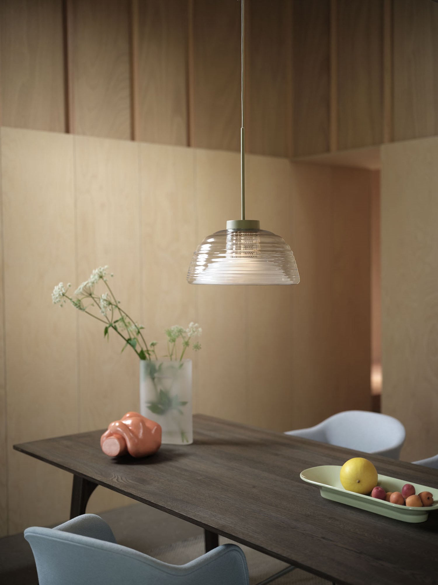 A Muuto setup featuring an olive Two-Layer pendant light above an Earnest table in dark oiled oak. The arrangement includes a Ridge vase in white frosted glass and a Fiber armchair with Acca 731 upholstery. The combination of the pendant's rich color, the table's dark wood, and the elegant vase creates a sophisticated and balanced look. A Muuto setup featuring an olive Two-Layer pendant light above an Earnest table in dark oiled oak. The arrangement includes a Ridge vase in white frosted glass and a Fiber armchair with Acca 731 upholstery. The combination of the pendant's rich color, the table's dark wood, and the elegant vase creates a sophisticated and balanced look.