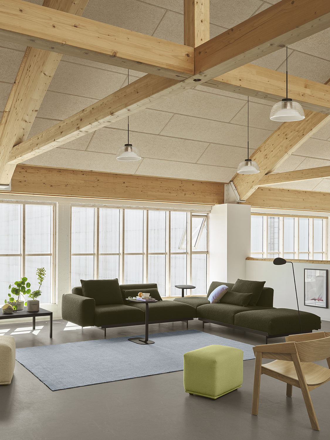 In Situ Sofa in a dark tone placed in a modern room, complemented by a light blue rug and glass pendant lamps for a stylish, contemporary atmosphere.