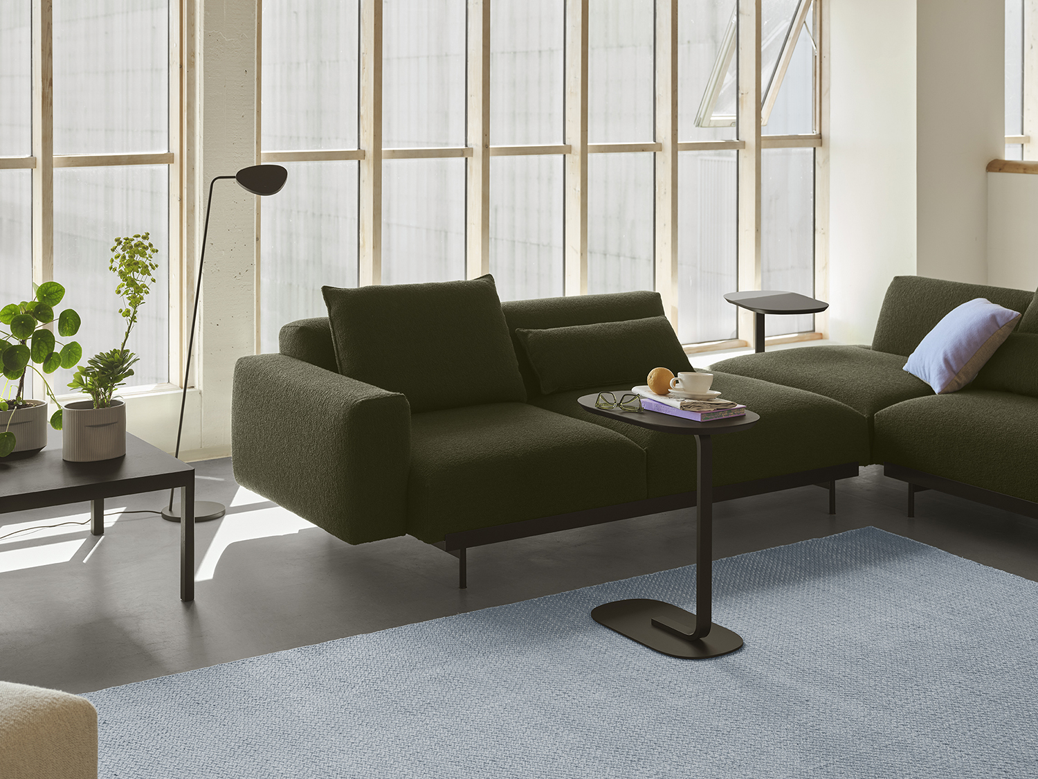 In Situ Sofa in a dark color positioned between a modern floor lamp and a simple sofa table, creating a clean Nordic look.