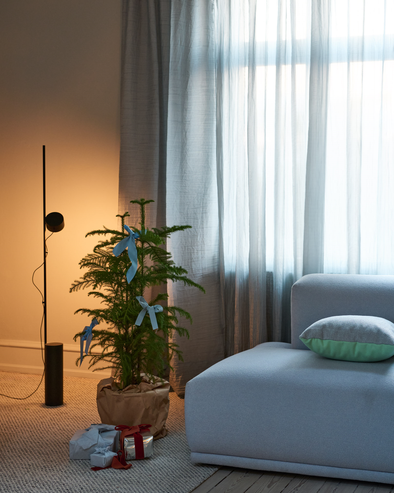 Image of a Muuto Mingle Cushion placed beside a Muuto Post floor lamp, creating a warm and inviting atmosphere in a cozy holiday 2024 decor setting